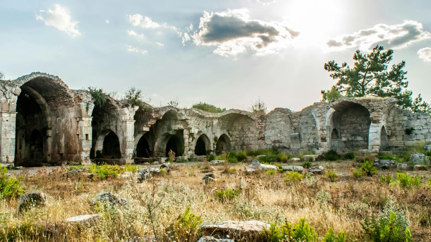 an abandoned building with sun coming through the cloudy sky