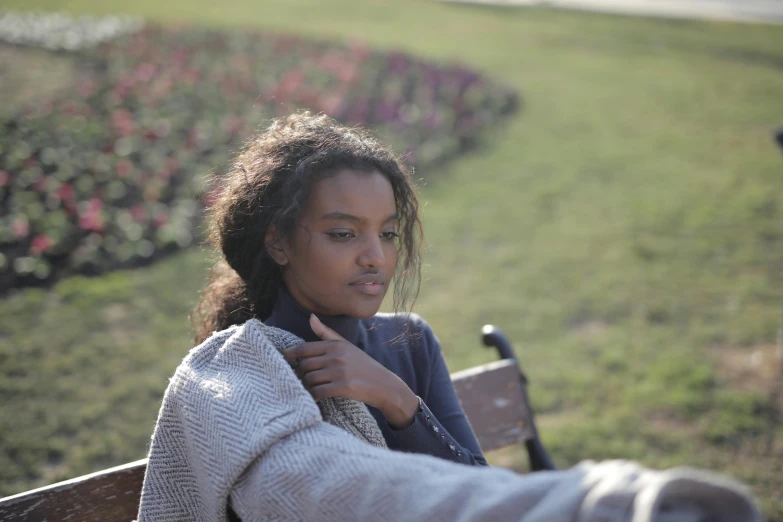 a close up of a person sitting on a bench near flowers