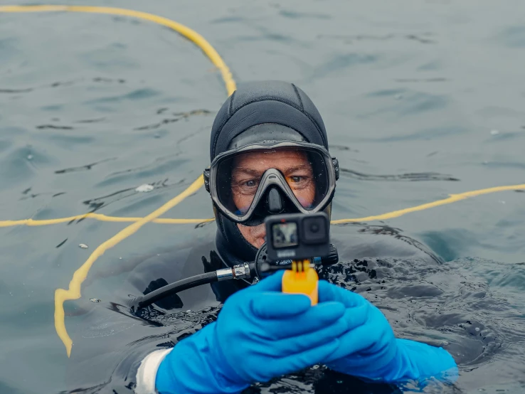 a scuba man in the water with his camera attached to a water rope