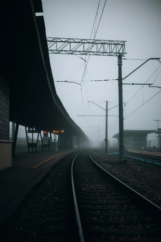 train tracks with power lines on a foggy day