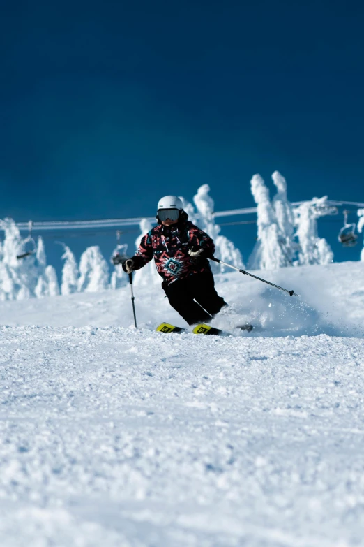 a man wearing a helmet while skiing down a snow covered hill