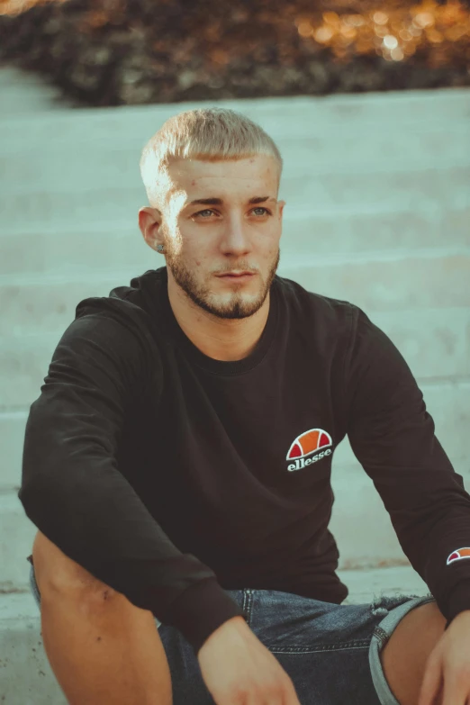 the young man is sitting on stairs with his hand on his knee