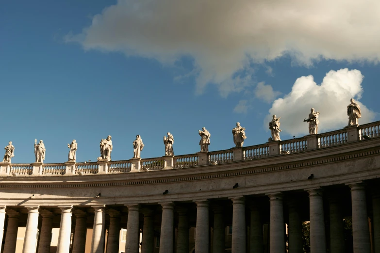 many statues atop a building that has many columns
