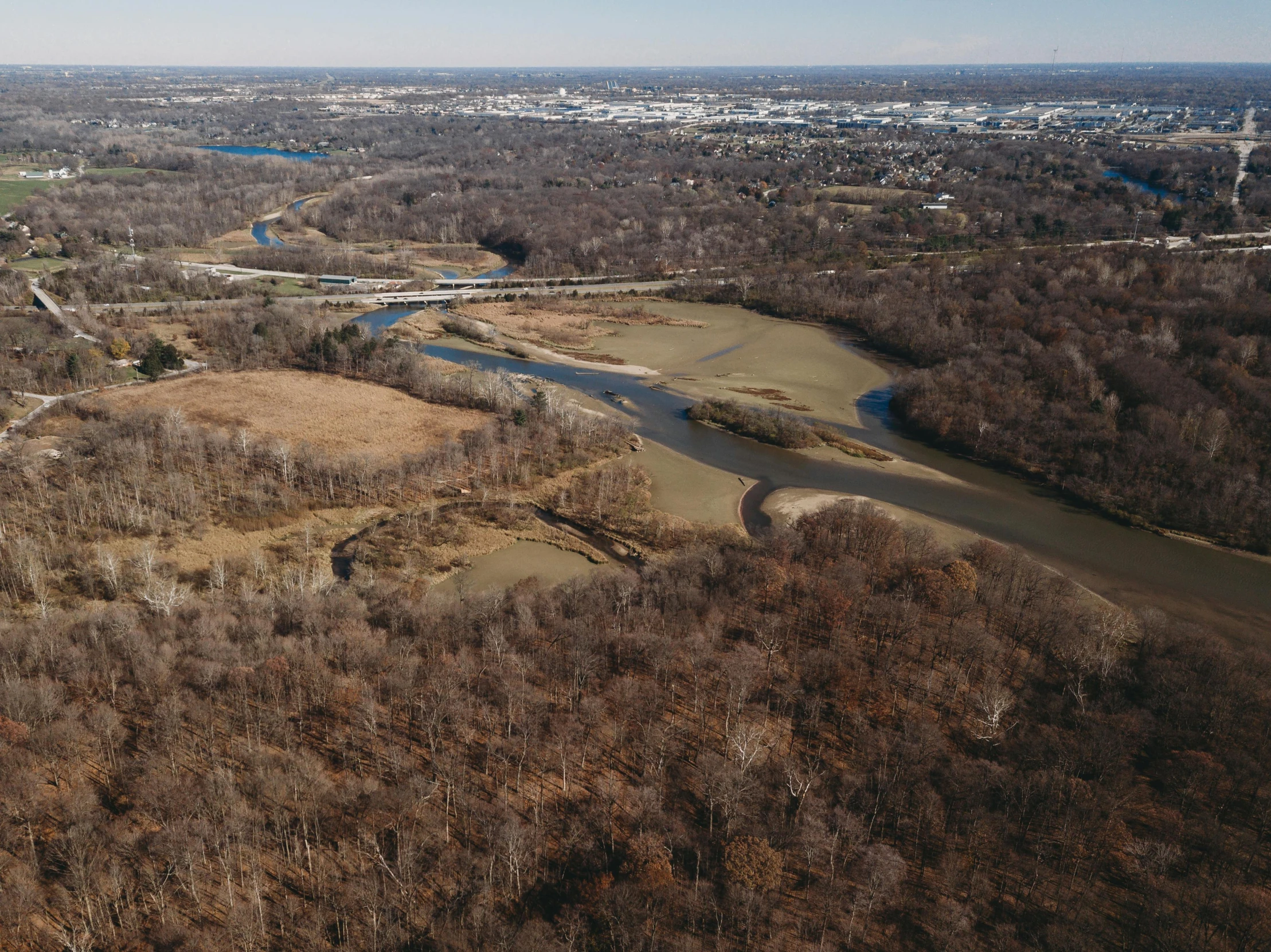 an aerial view of a lake surrounded by bare trees