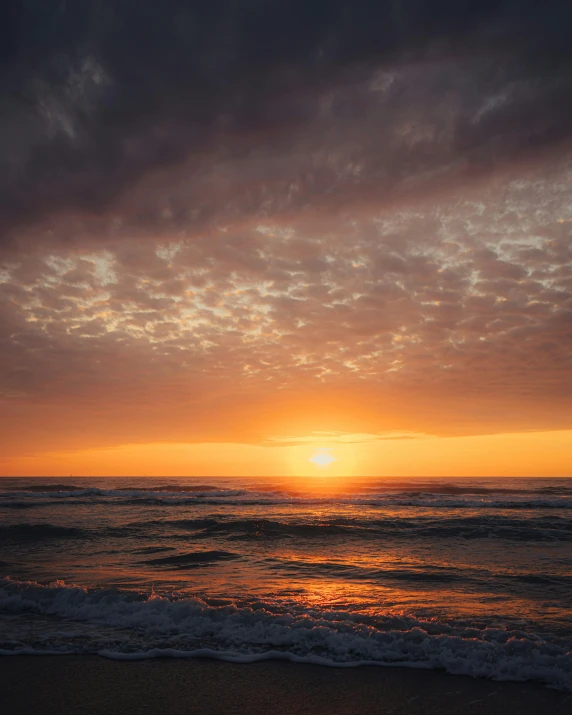 a sunset view of the ocean with a few surfers