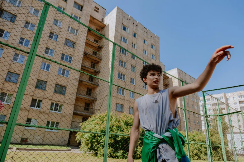 a young man holds out his arms in front of a tall building