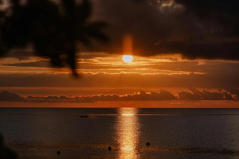 a sunset reflecting a boat in the water