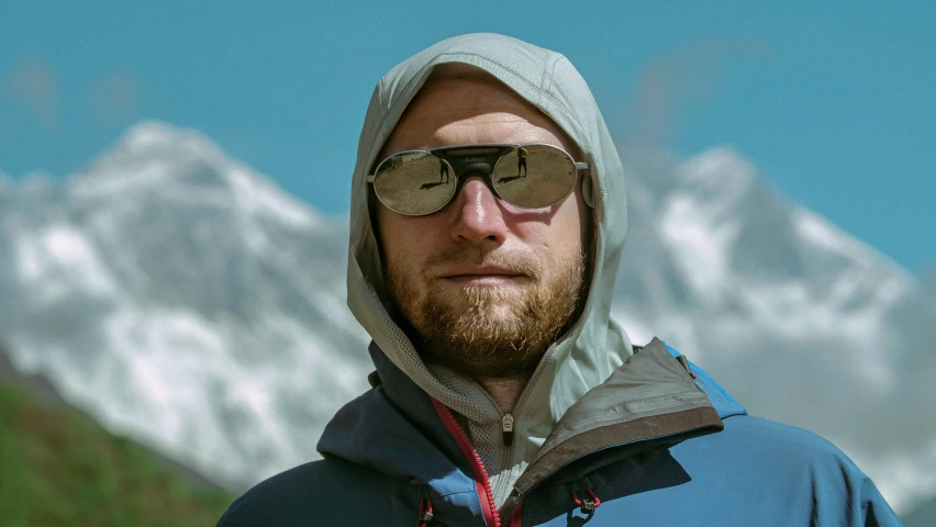 a man with sunglasses standing in front of some snow covered mountains