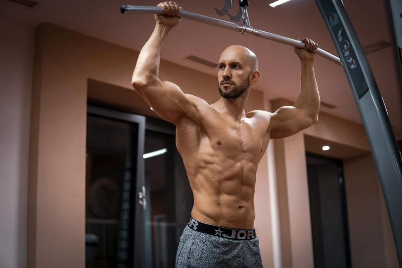 a shirtless man with  is doing a pull up in the gym