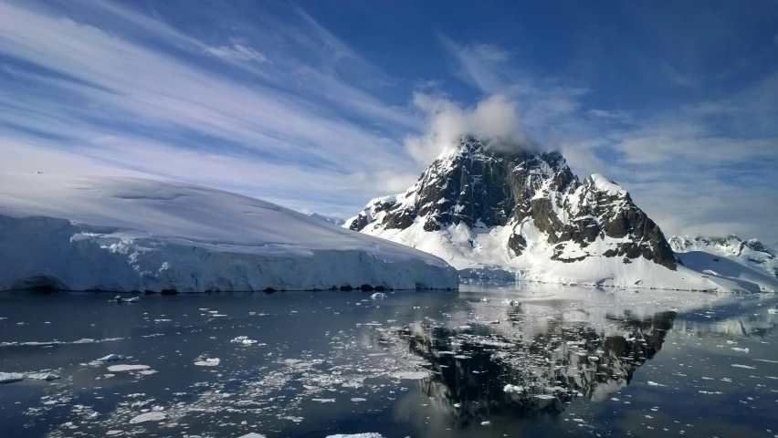 a very tall mountain covered in ice next to water