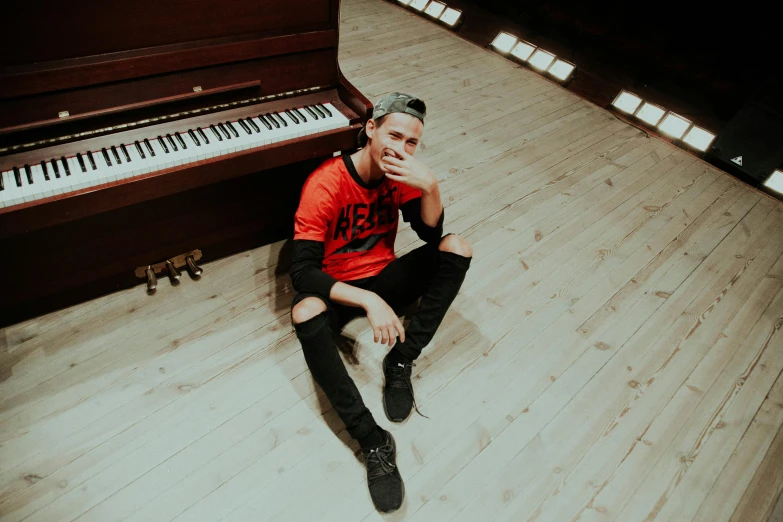 a man sitting on the floor in front of an old piano