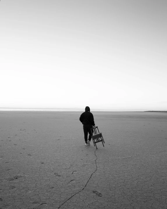 a person walking through a flat field holding a ladder