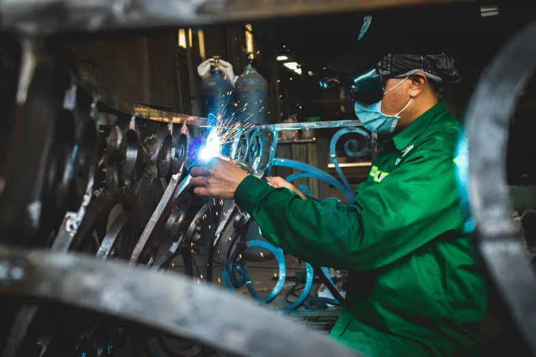 a woman in green jacket using a welding tool