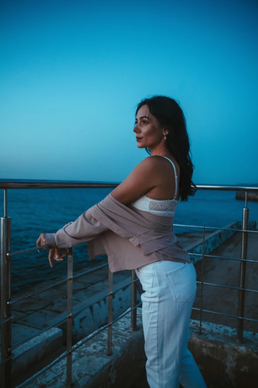 a woman with a back leg is posing on a railing by the ocean