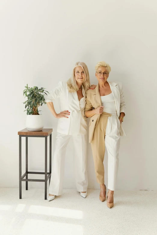 two women stand in white attire next to each other