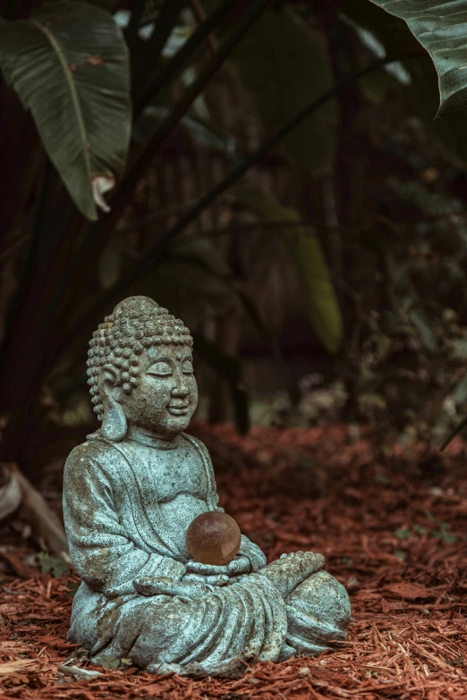 a buddha statue sitting on the ground with his head resting on a bowl