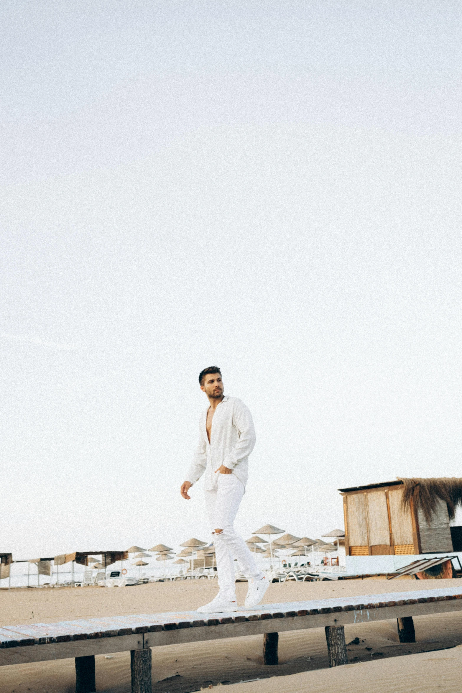 the man is standing on the boardwalk beside the buildings