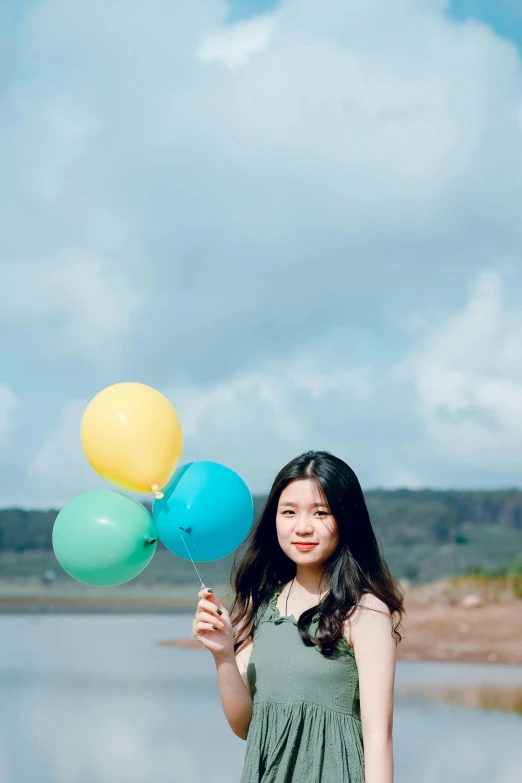 a woman in dress holding several balloons