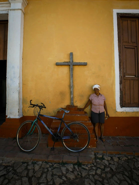 a bike with a man next to it standing beside a cross