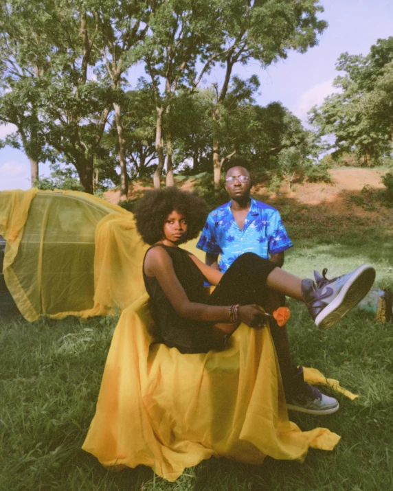 two people sitting on the grass next to a large tarp