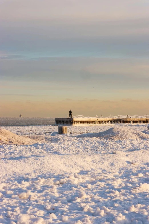 a pier sitting above snow covered ground next to a body of water