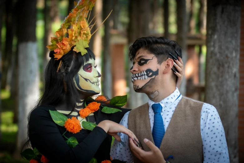 a man and woman wearing face paint standing in front of trees