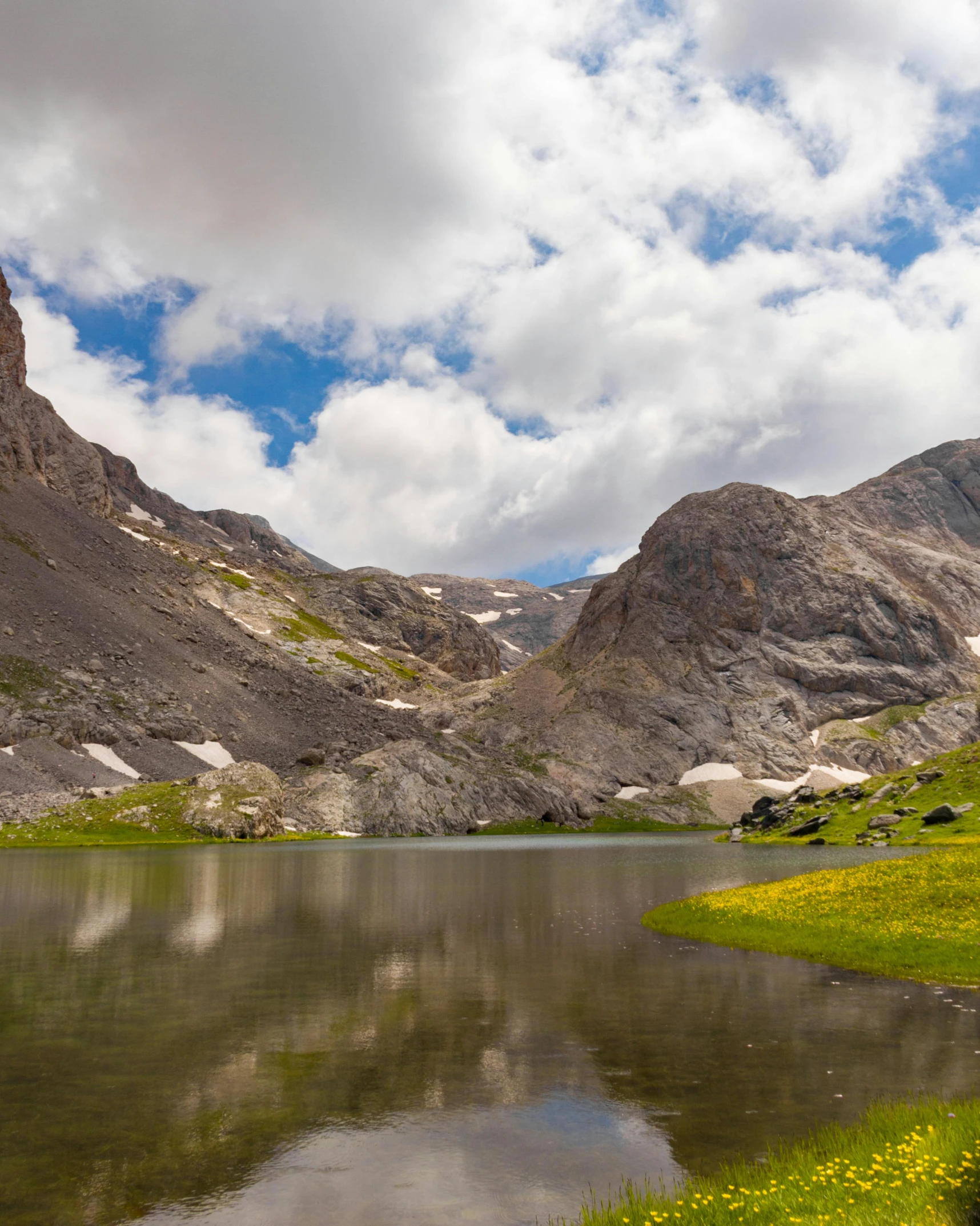 a mountain range with a lake surrounded by lush green grass