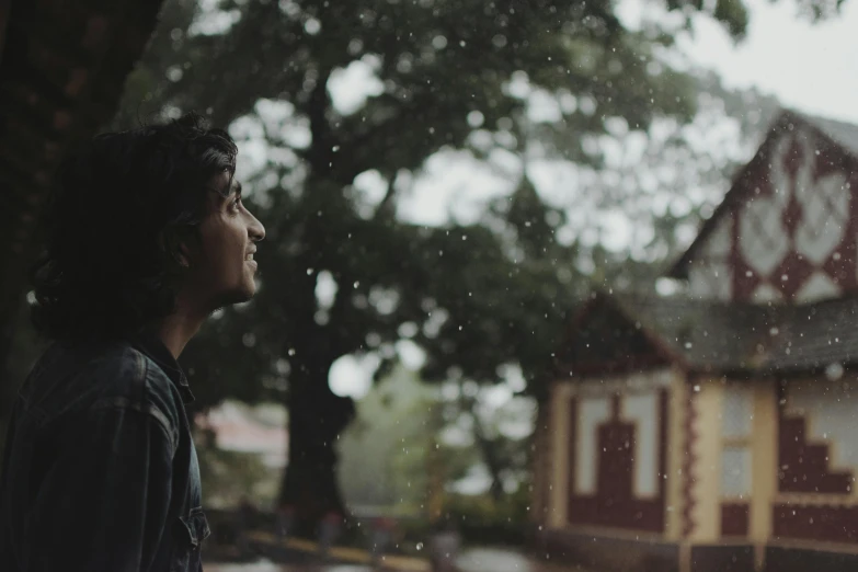 an asian man looking out of a window on a rainy day