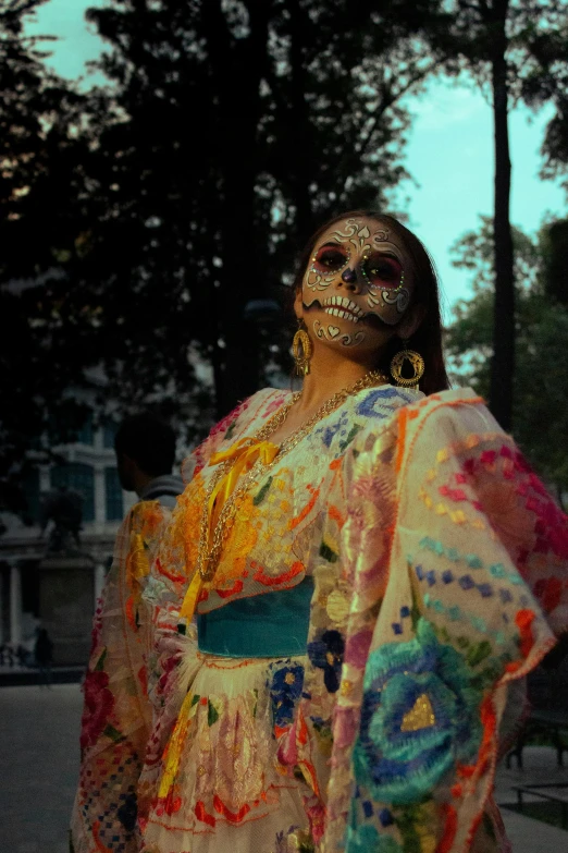 a woman in face paint stands next to a tree