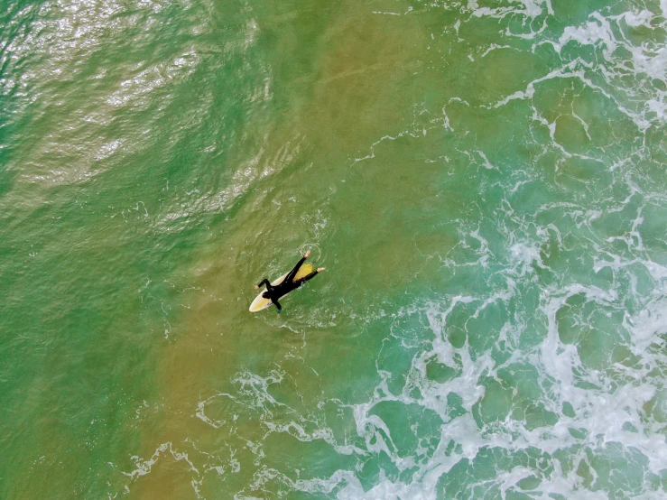 an aerial view of a man surfing in the ocean