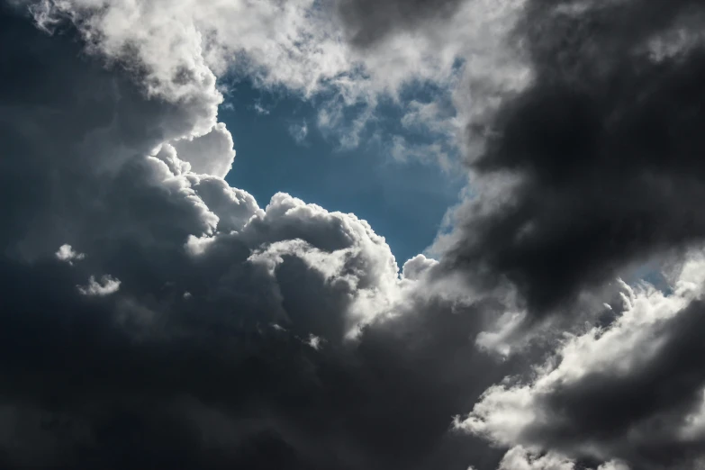 a plane flying in the sky near many clouds