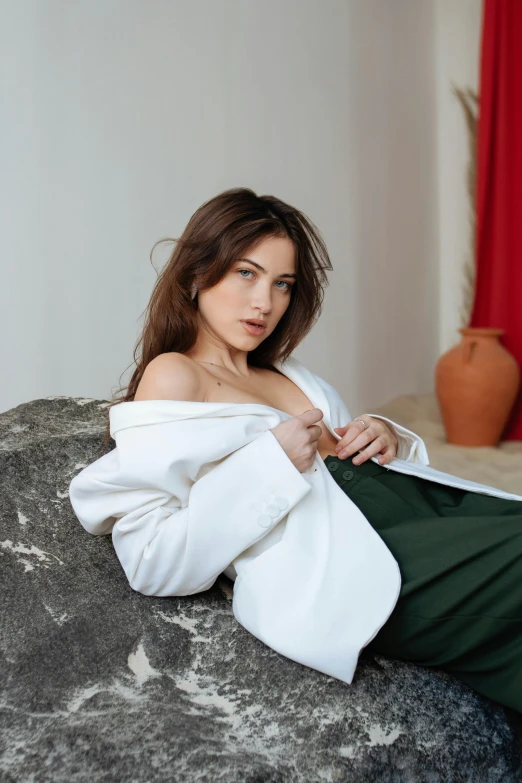 a beautiful woman sitting on top of a couch wearing a white jacket