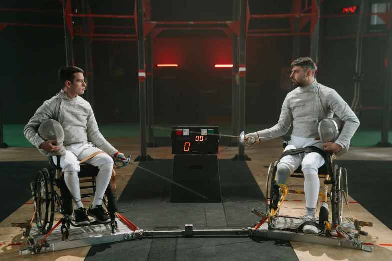 two men sitting on wheelchairs holding tennis rackets