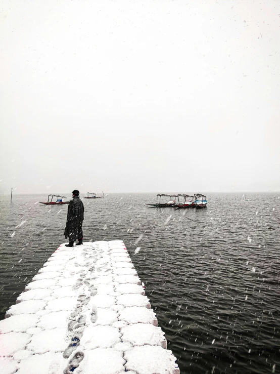 a man standing on top of a long jetty covered in snow