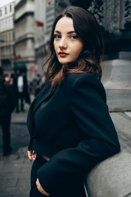 a woman in a suit is posing on the street