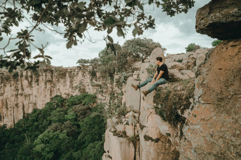 man sitting on a cliff with his legs crossed