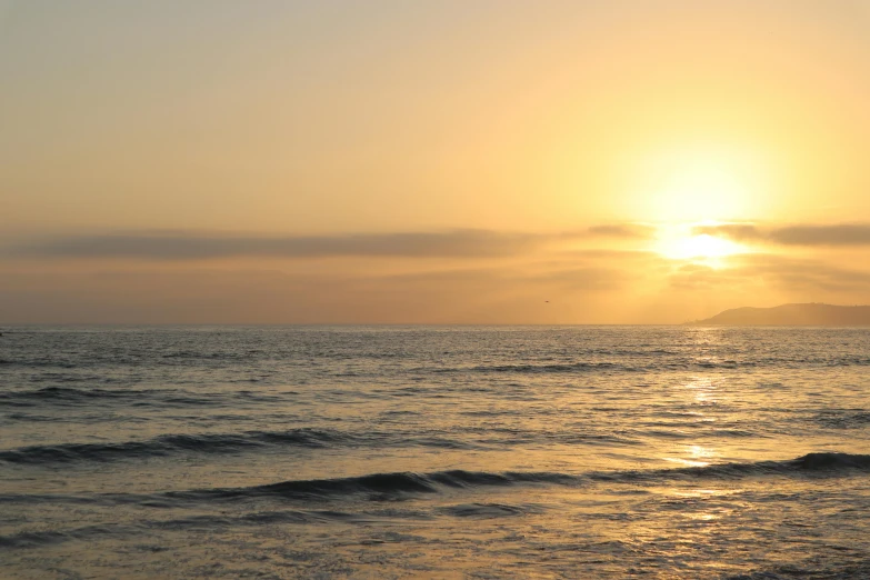 a boat sails in front of the setting sun