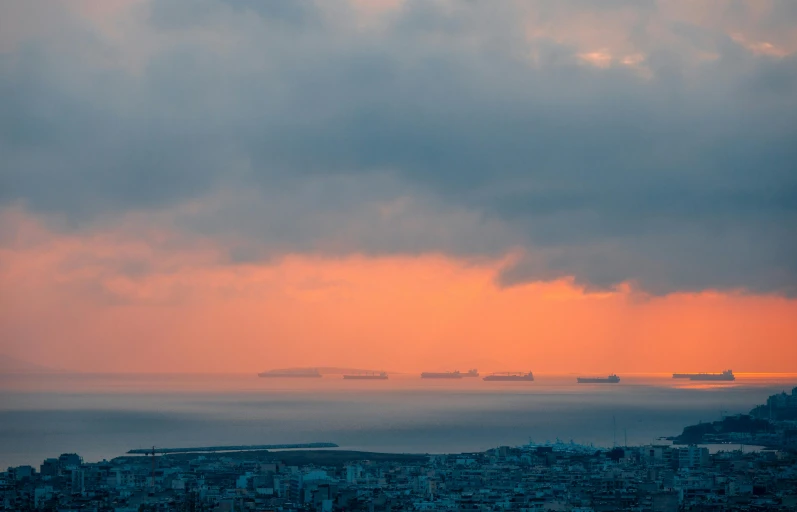 boats in the distance are sailing towards sunset