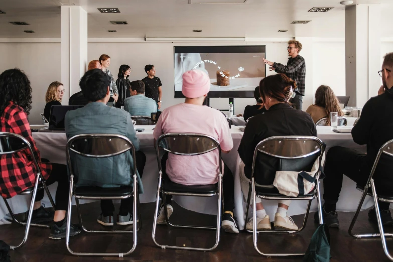 several people sit at a table in front of a projection screen