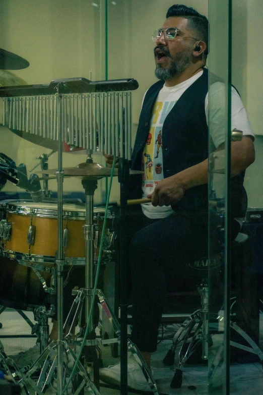 a man playing drums while standing behind a microphone