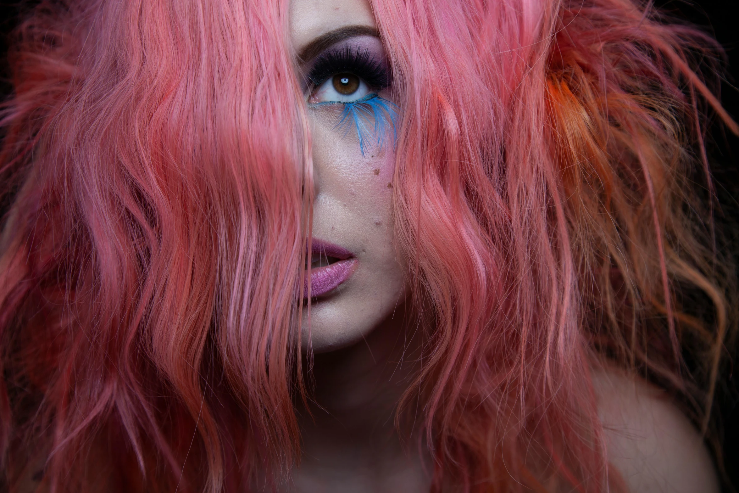 a close up of a woman with blue and pink makeup