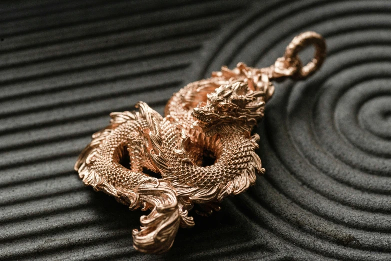 a gold snake charm sitting on top of a metal table