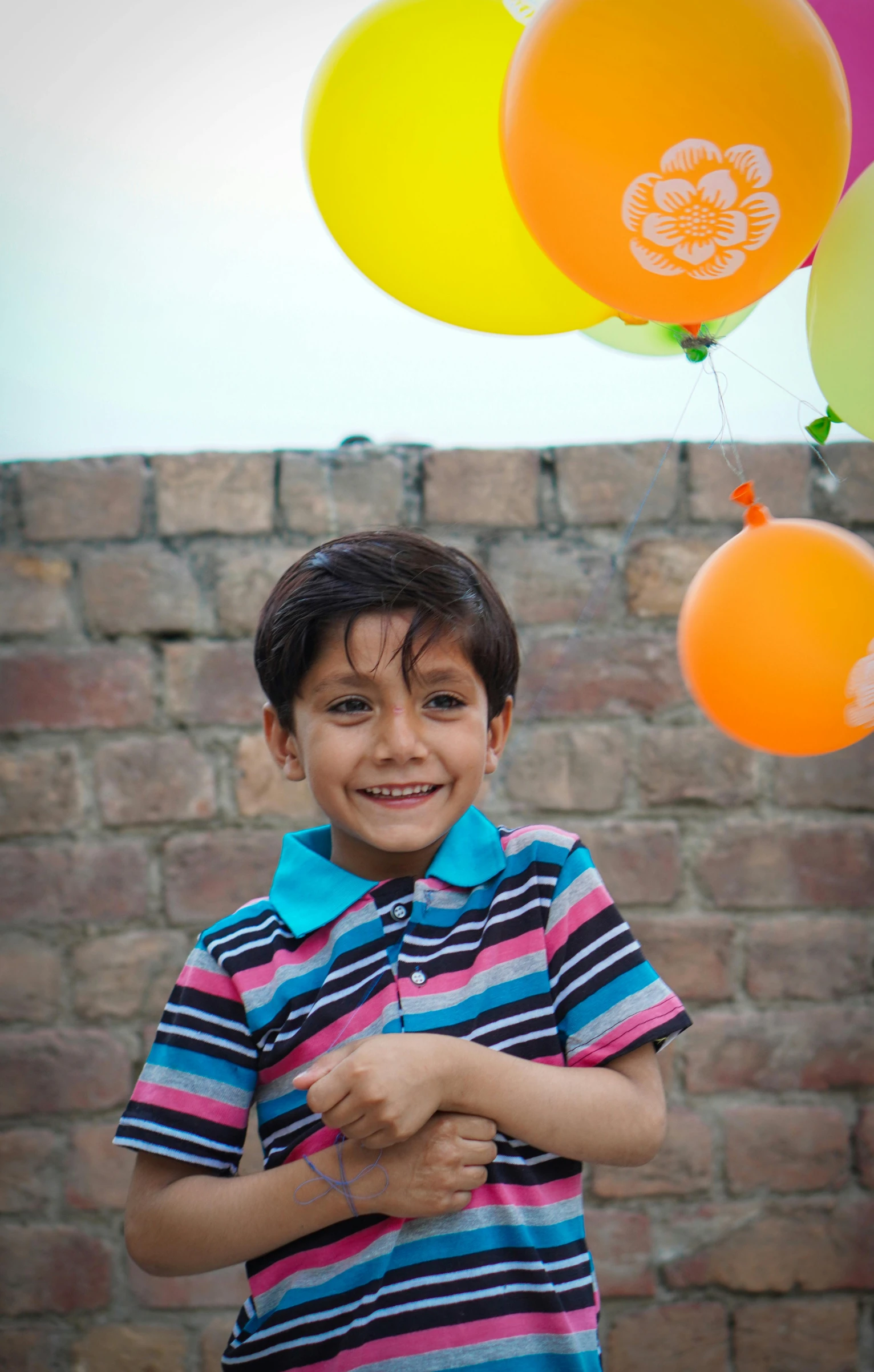 the boy smiles while holding balloons that say happy