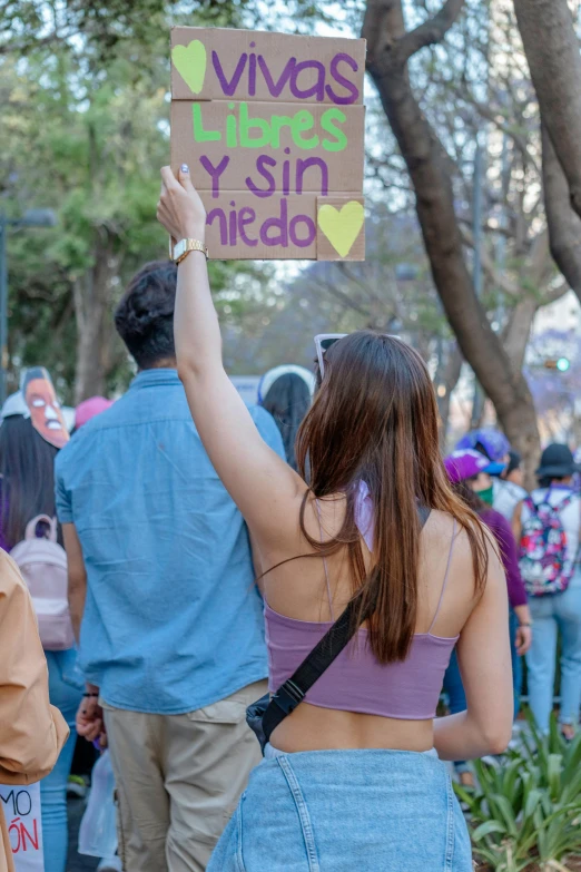 a man and woman holding up a sign in the park