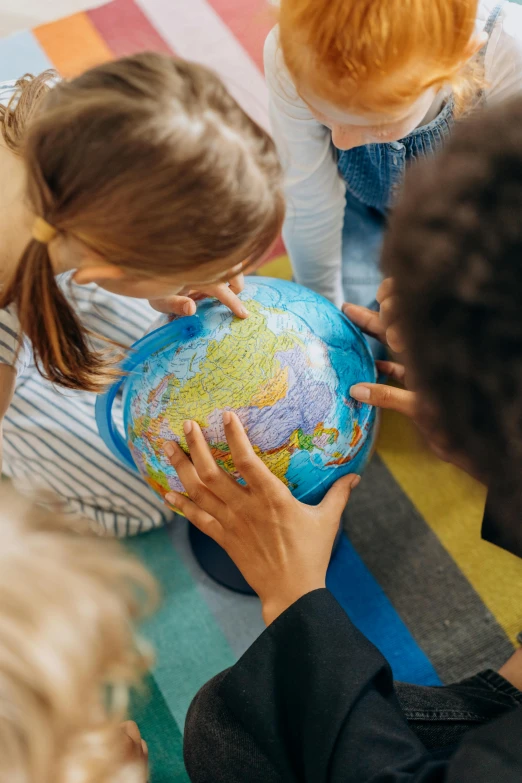 s are standing around a small globe and interacting with it