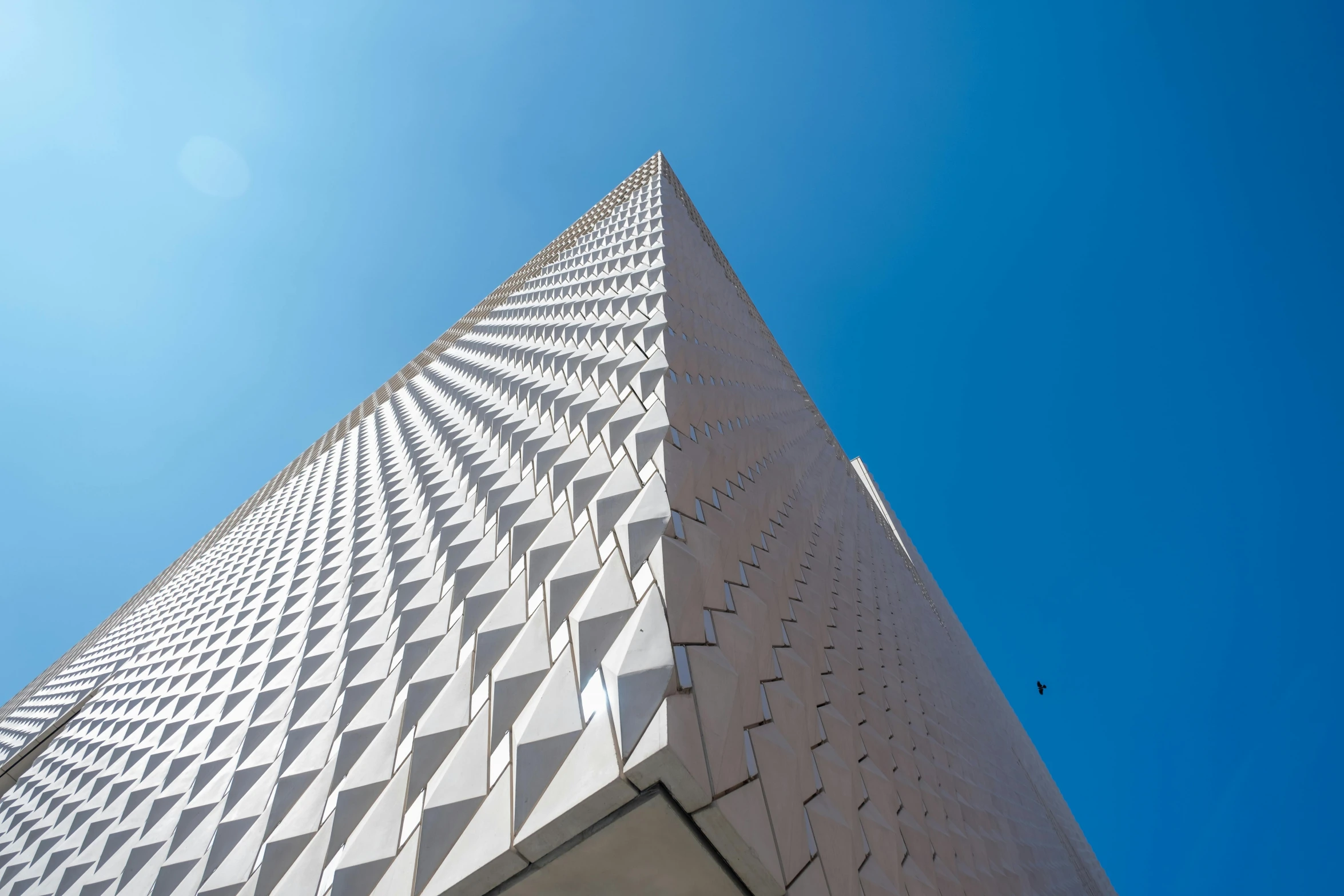 the top of a tall building that has a white triangular pattern on it