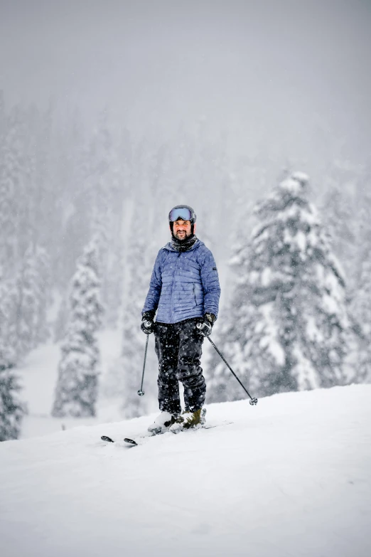 the skier stands with his ski poles on the mountain