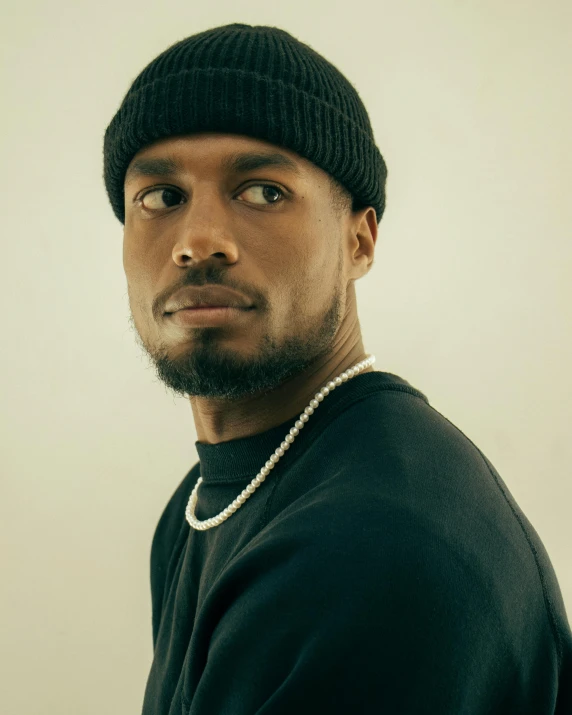 a young man wearing a hat, jacket and pearls