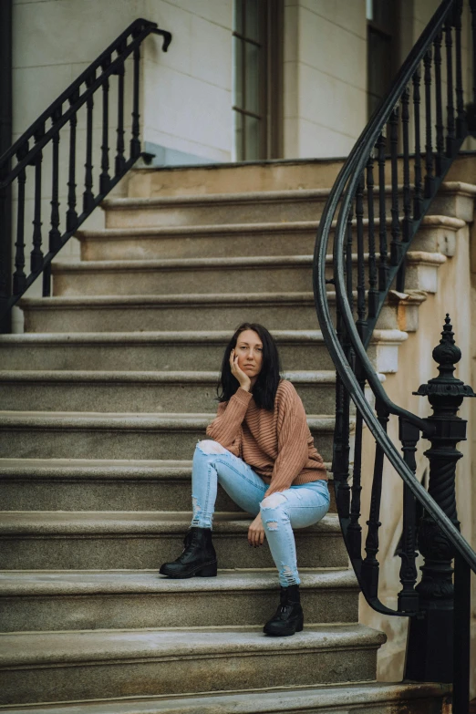 a woman wearing blue jeans sits on the steps