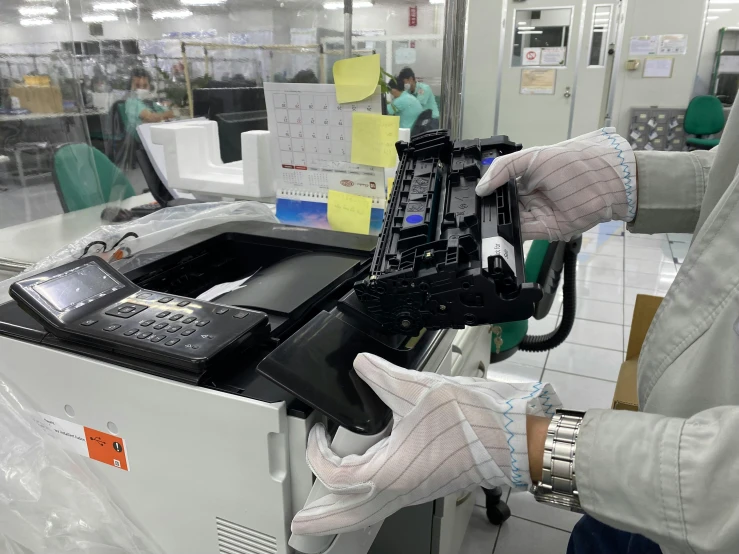 a person with gloves operating a machine in a factory